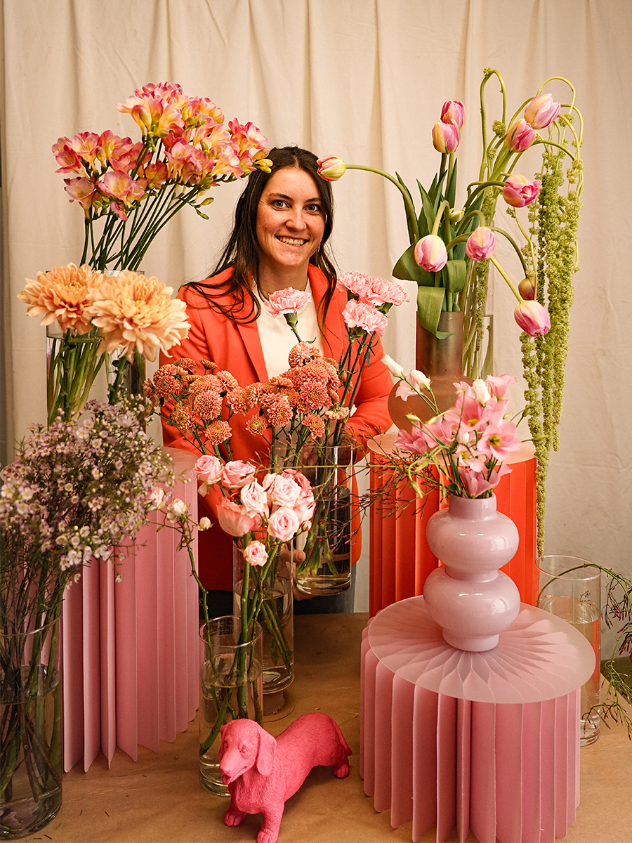 Anbabell hinter verschiedenen Blumengestecken